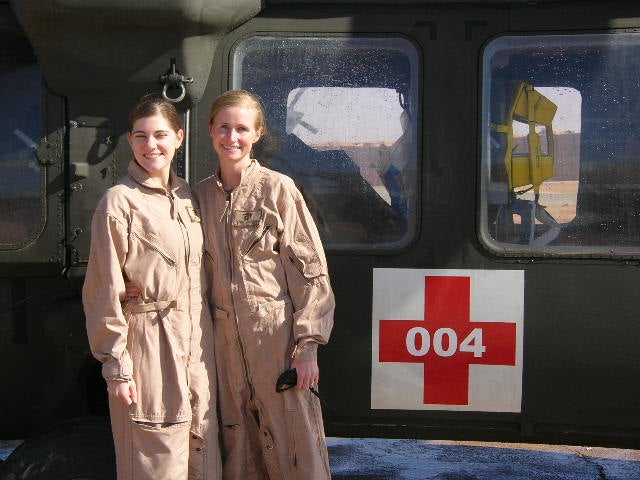 Jenny Alderden stands in a flight suit next to another flight nurse by their helicopter.
