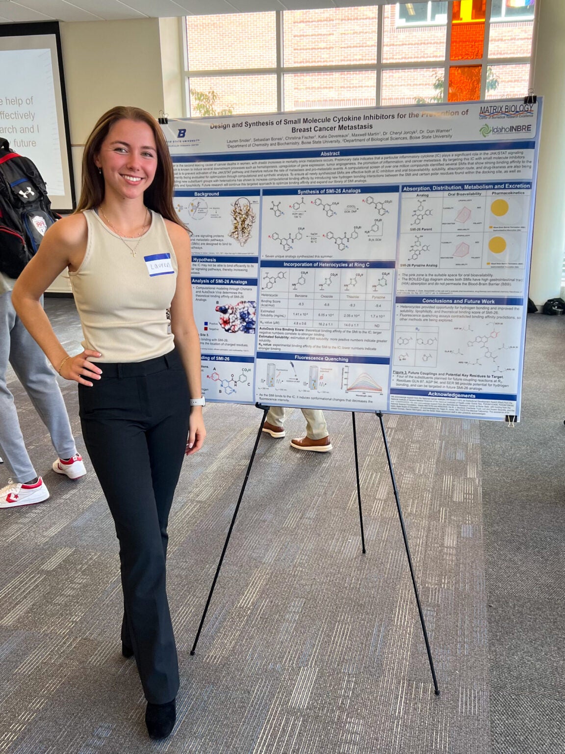 student stands next to her research poster at Idaho Conference on Undergraduate Research