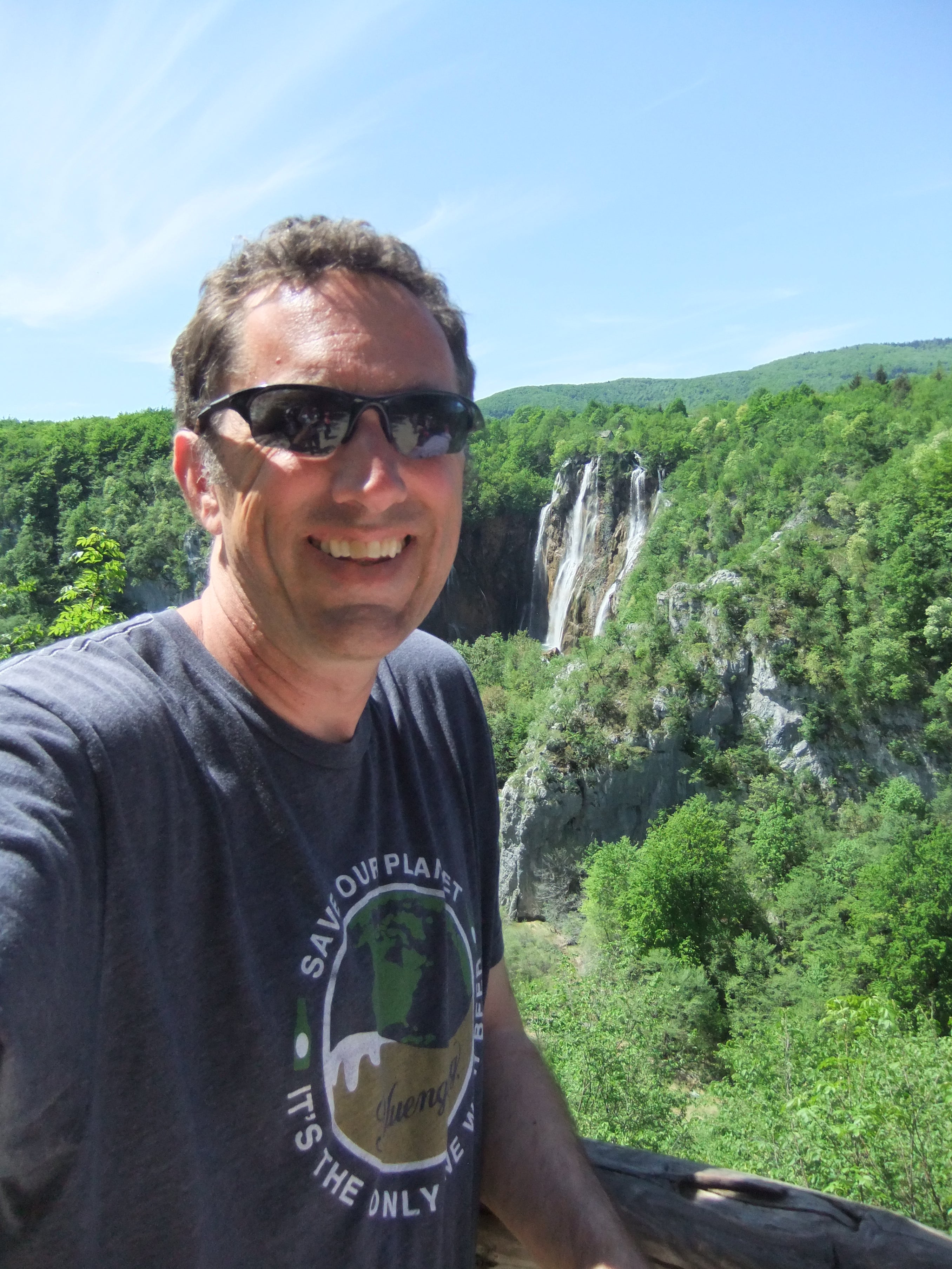 Nick Miller selfie portrait in front of a waterfall in a tropical climate.
