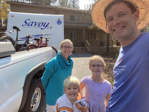 Reinhardt and family, wife and two young children, standing next to truck with bikes in the back and trailer hooked up