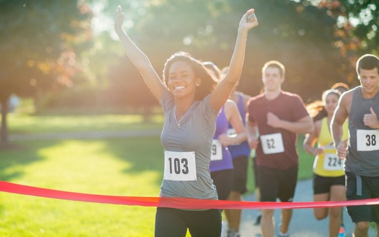 Happy people running across the finish line of a marathon