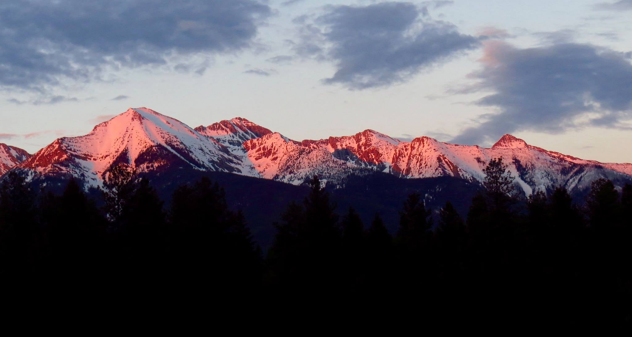 snow covered mountains glowing pink in the morning light