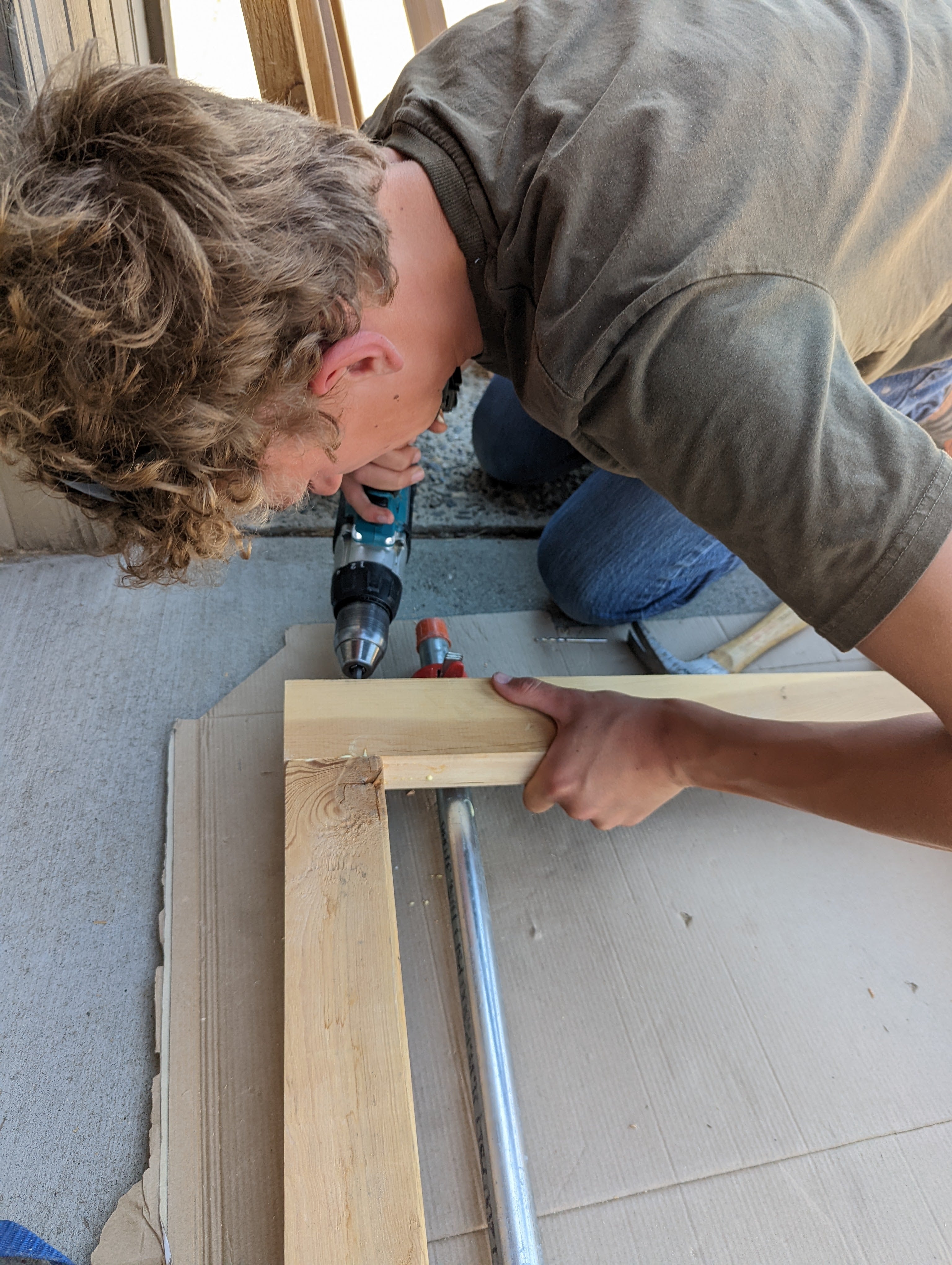 a teen uses a drill to attach two pieces of wood together
