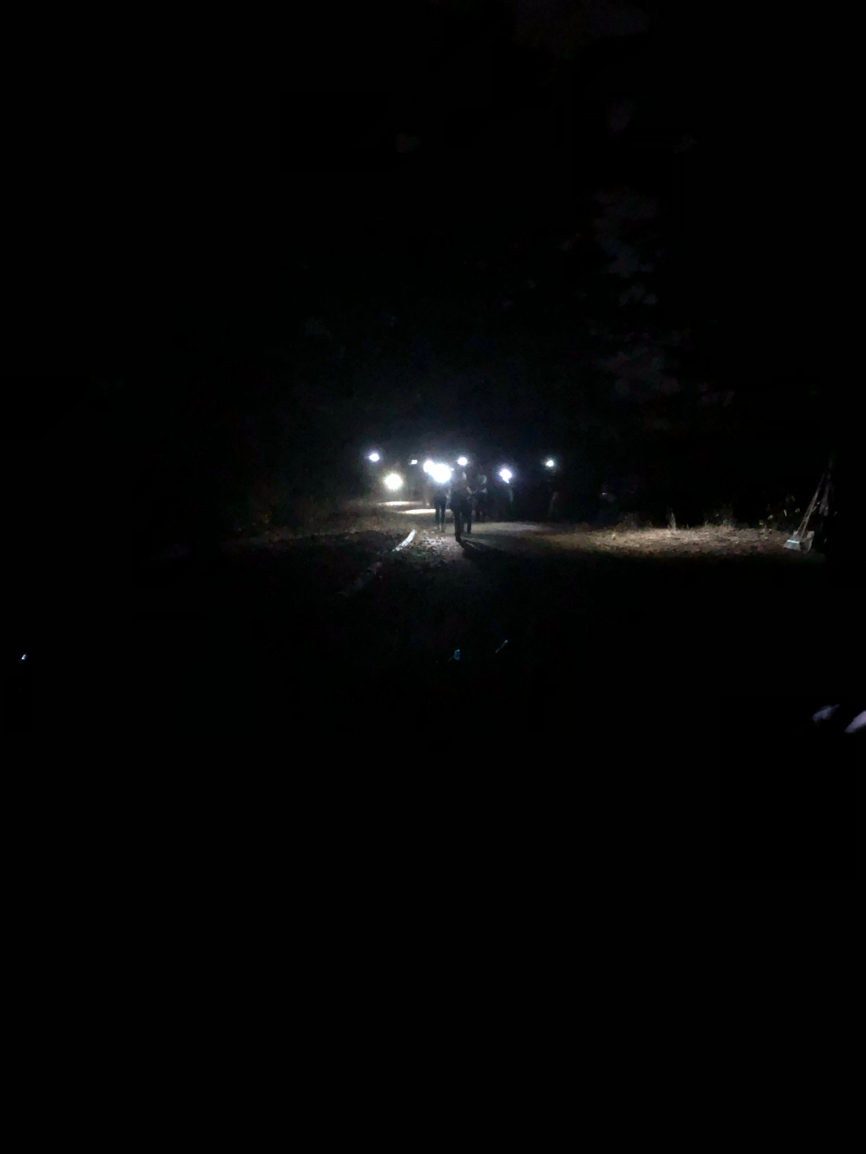 people with head lamps on, walking through the darkness