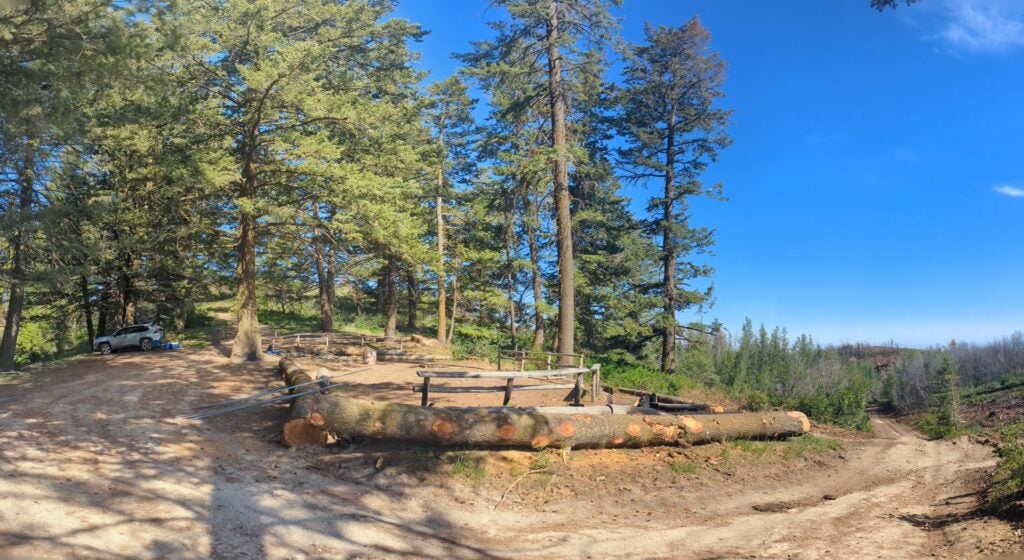 a classic and recogizeable view of Lucky Peak camp with tall douglas fir trees and log railings surrounding IBOs camping pads.