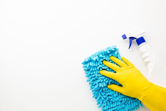 Image of a gloved hand with cleaning supplies