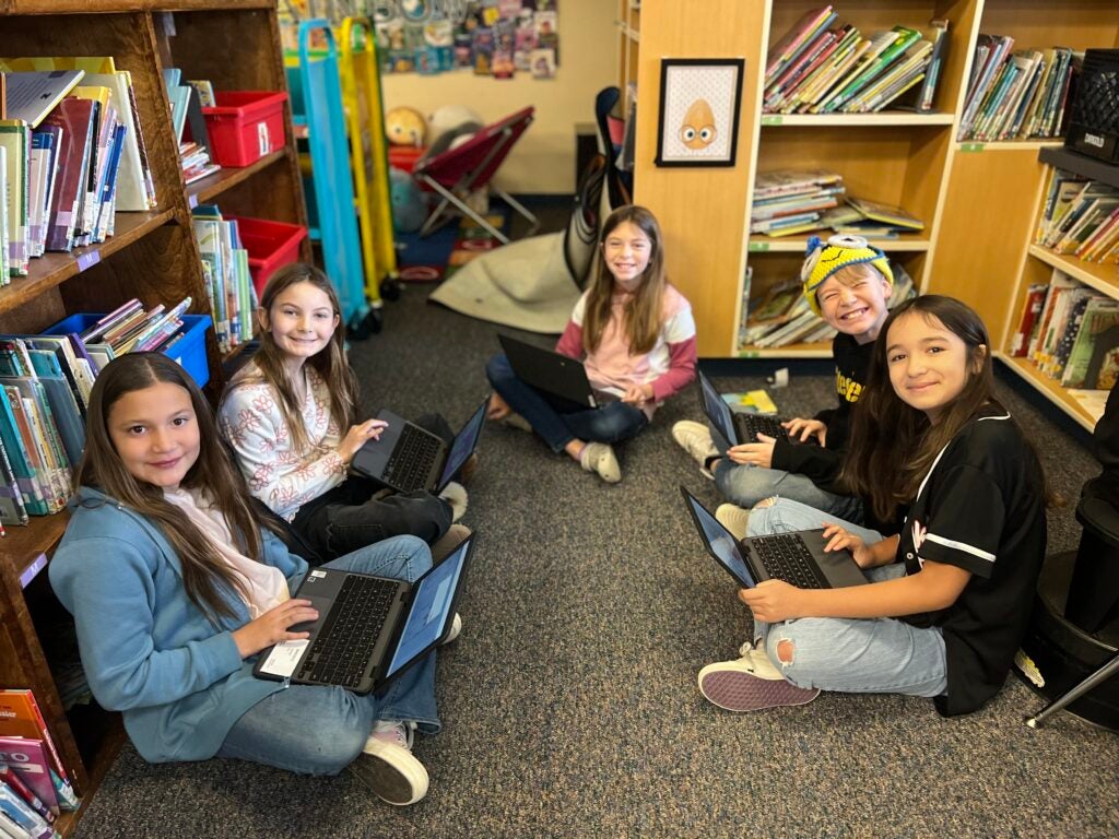 group of students sit in library with laptops