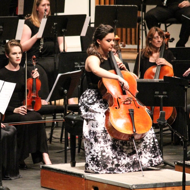 student playing cello with orchestra