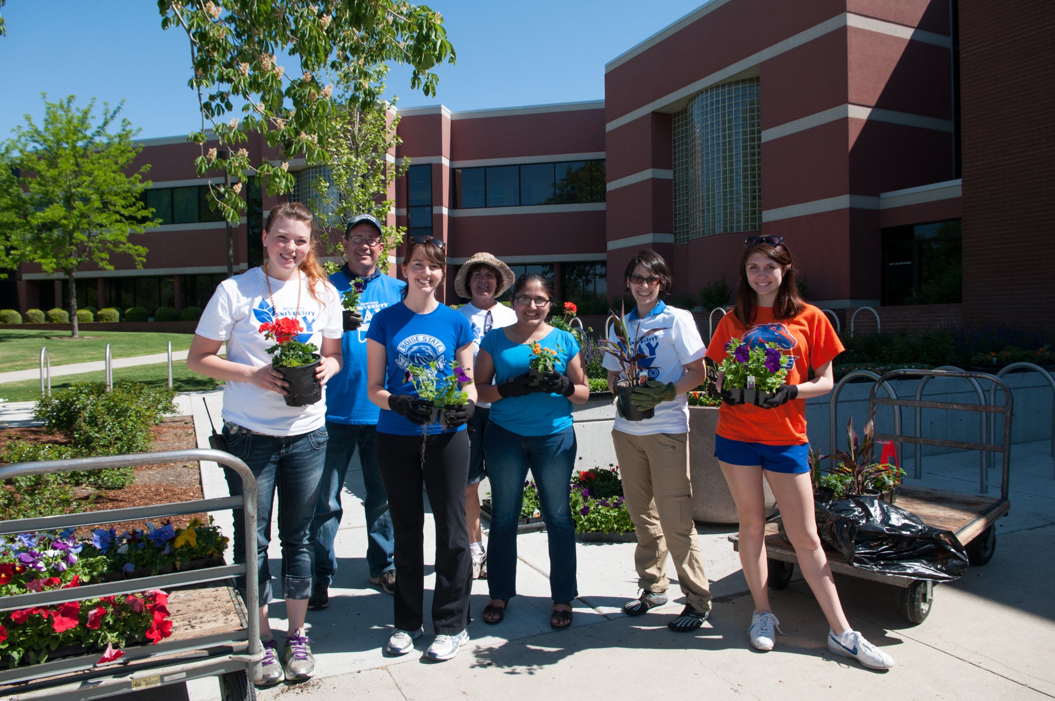 Students hold pots of flowers that are ready to be planted