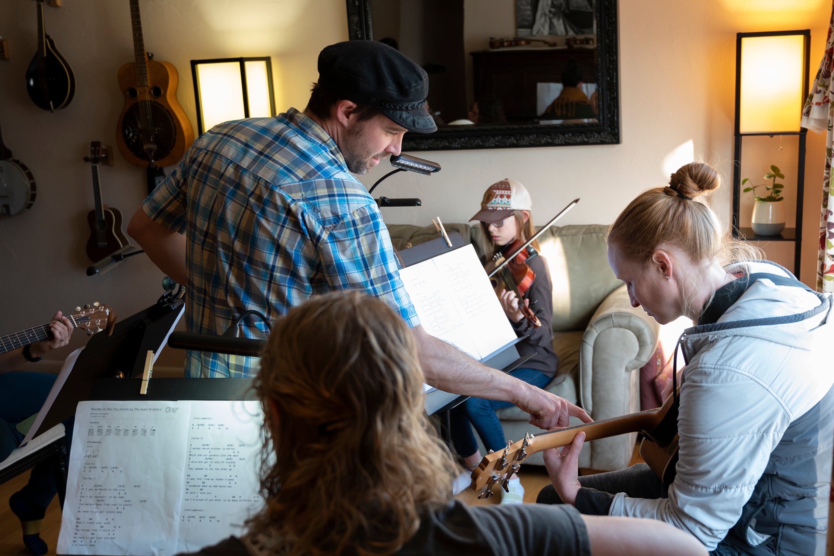 Group of people play a variety of musical instruments in a living room