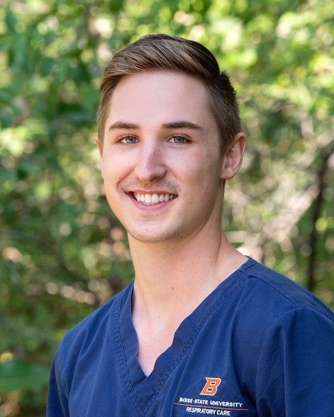 A guy poses outdoors in scrubs