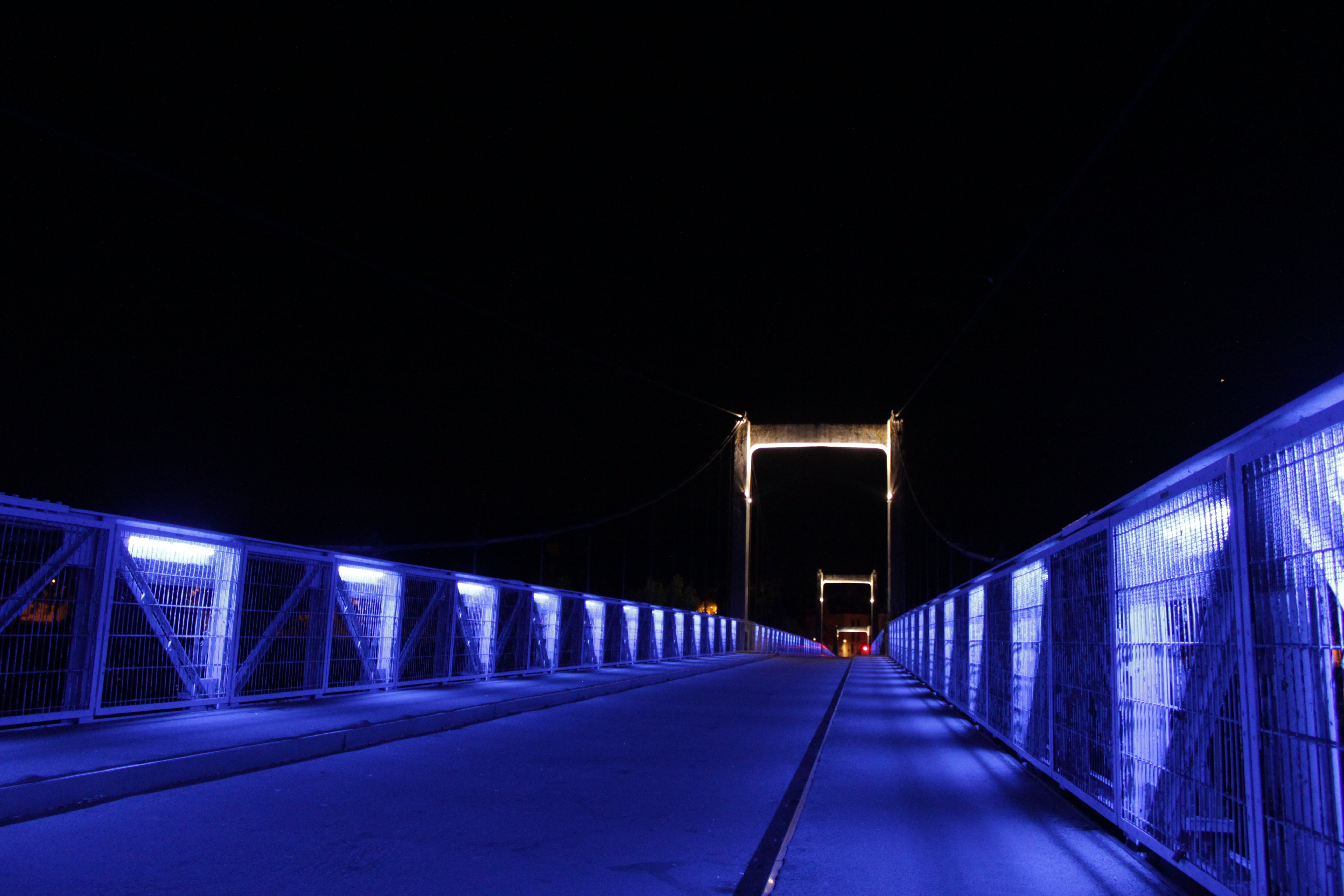 long blue-lit suspension bridge with two arches