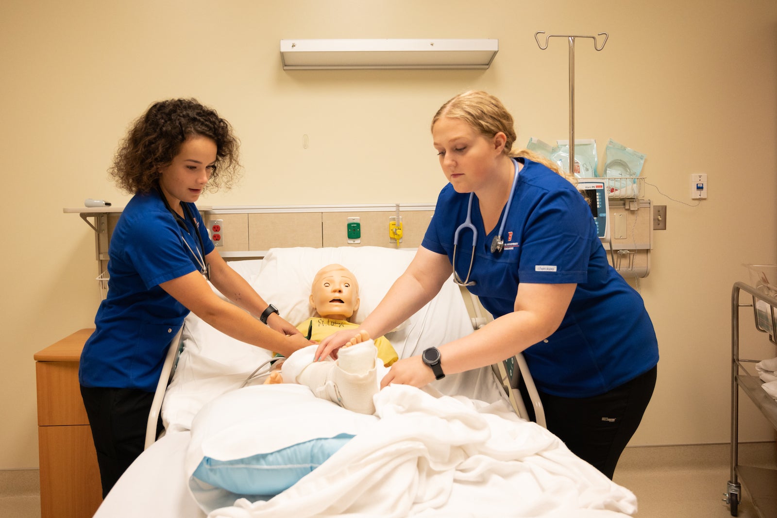 Two nursing students practice with a pediatric simulation doll