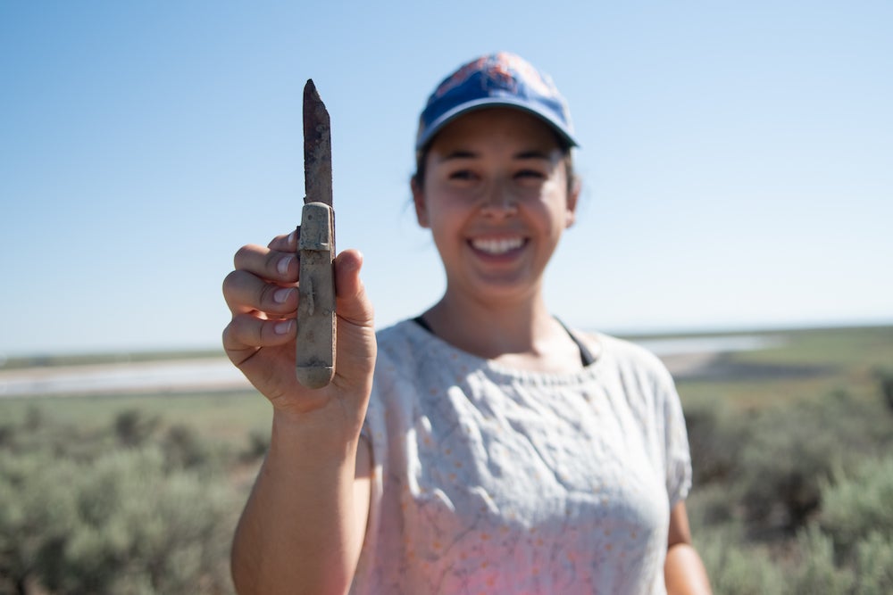 girl holds artifact (knife) found in desert