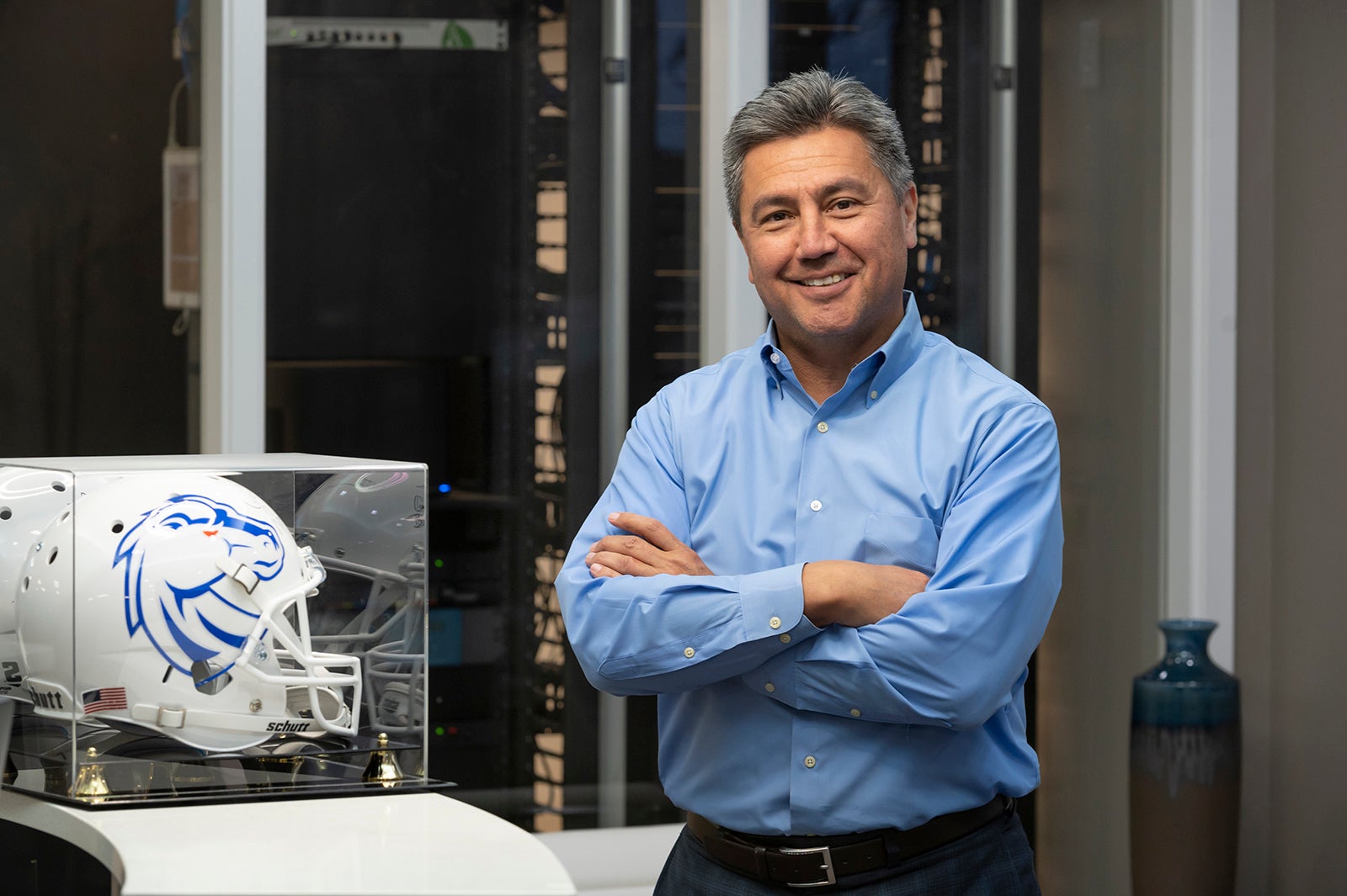 Greg Chavez stands next to a football helmet in a display case