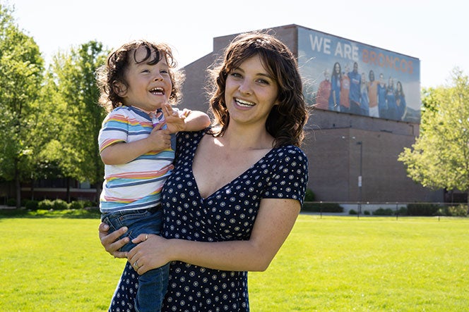 MSW Student Emma Ballantyne holds her son on Boise State's intramural field