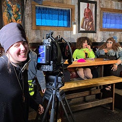 A film set in a bar with a cinematographer and two actresses sitting in a booth
