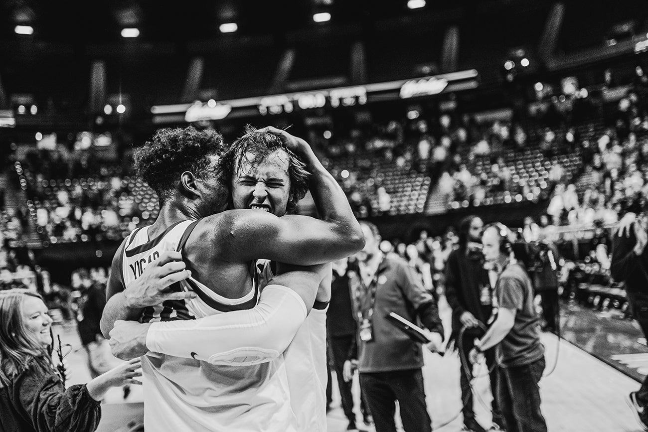 men's basketball team members hug after victory