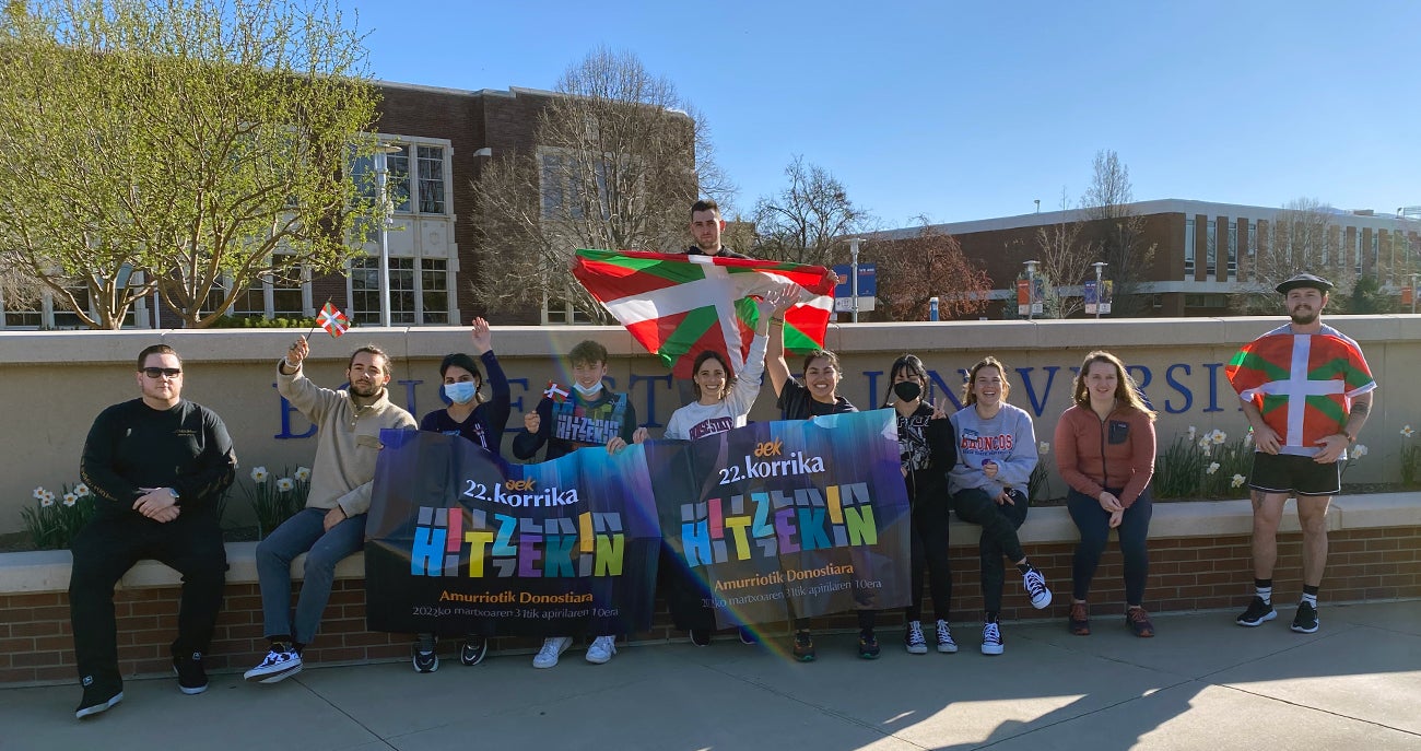 Students and faculty with the Basque Studies program outside the Admin building on campus with a banner that reads "Korrika 2022" and Basque Country flags