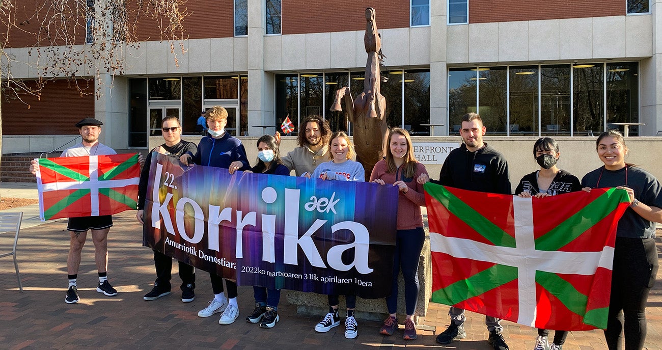 Students and faculty with the Basque Studies program outside Riverfront Hall with a banner that reads "Korrika 2022" and Basque Country flags