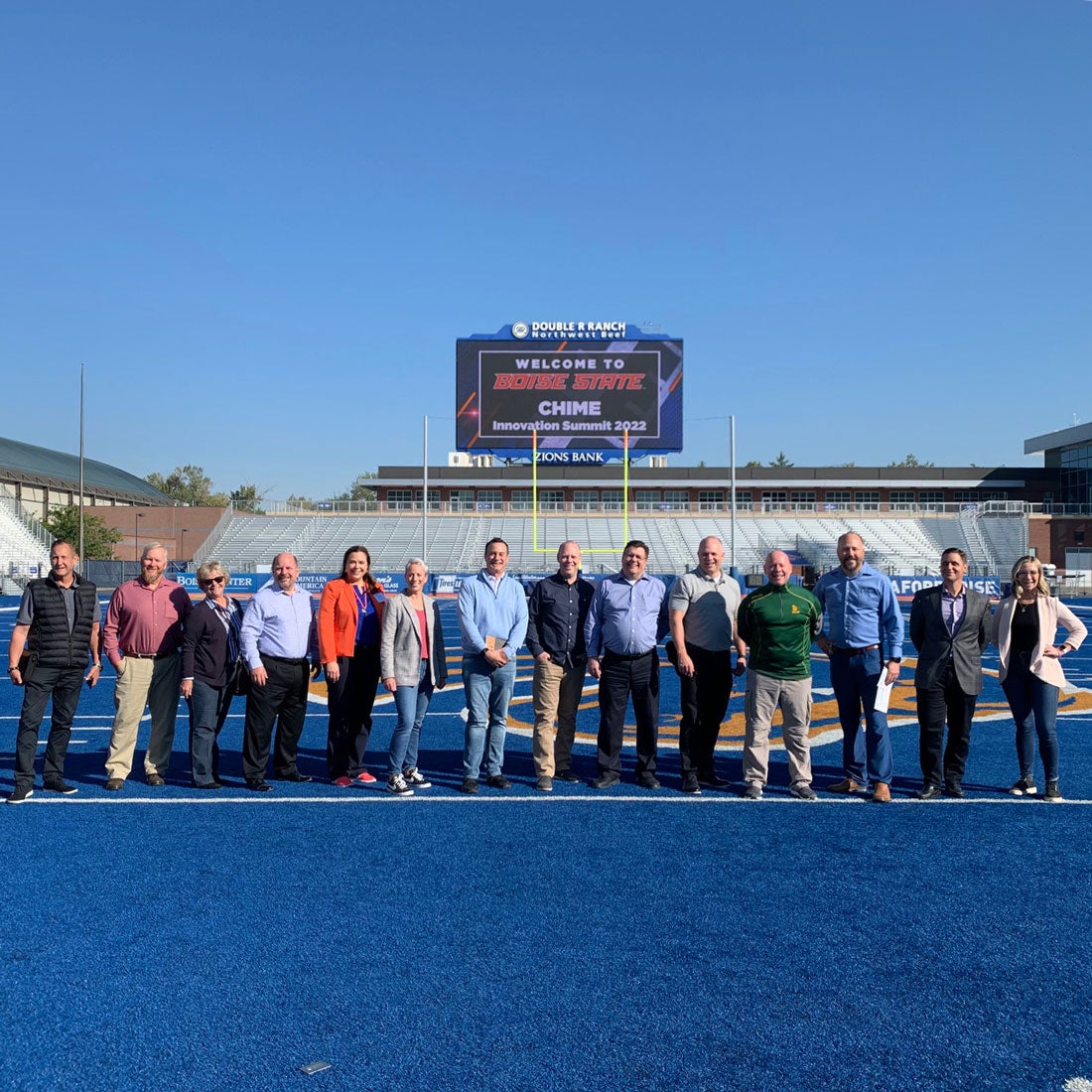 Members of the Innovation Summit stand in the middle of the Blue Turf field.