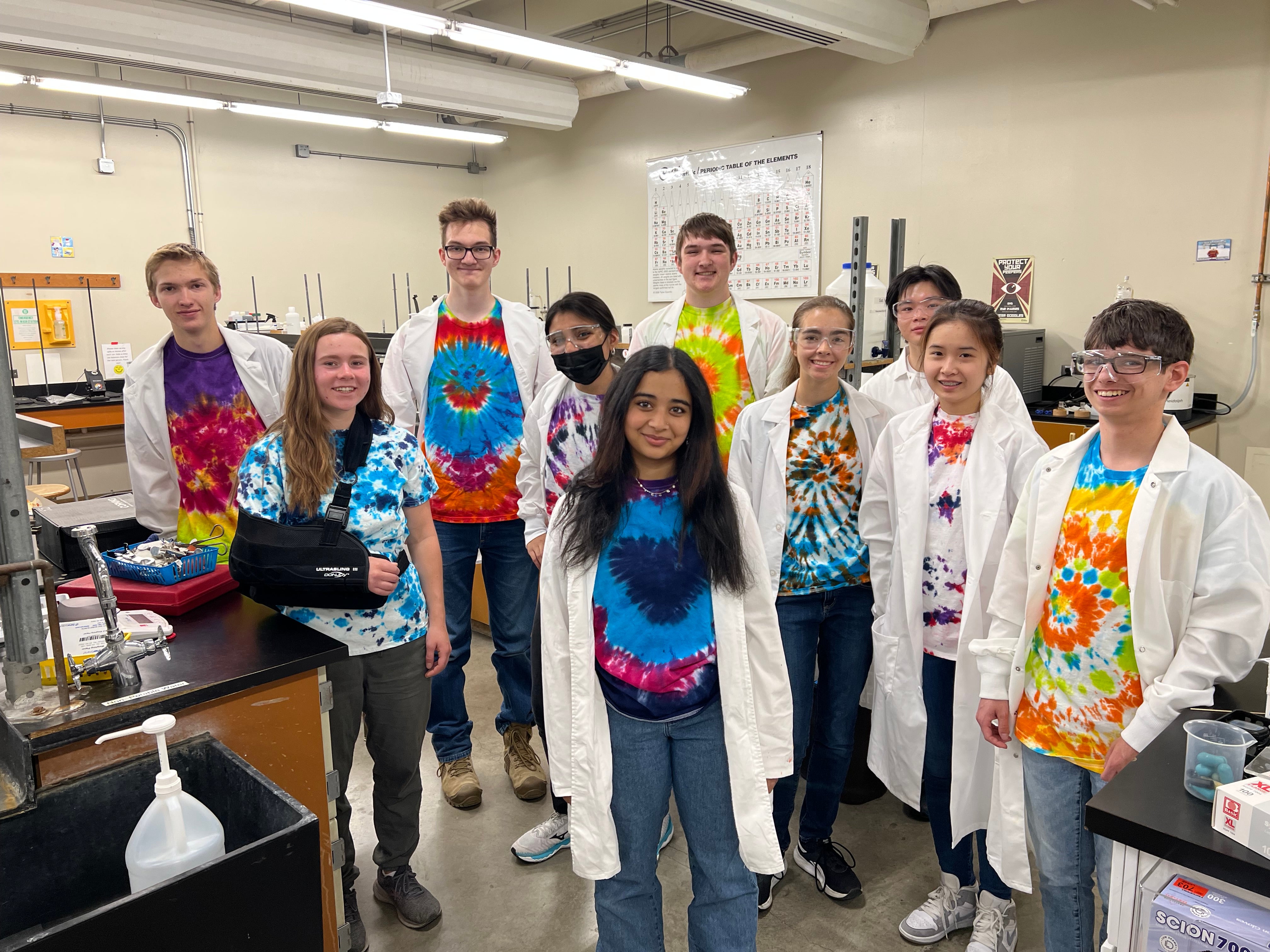 ten students pose in a lab wearing lab coats