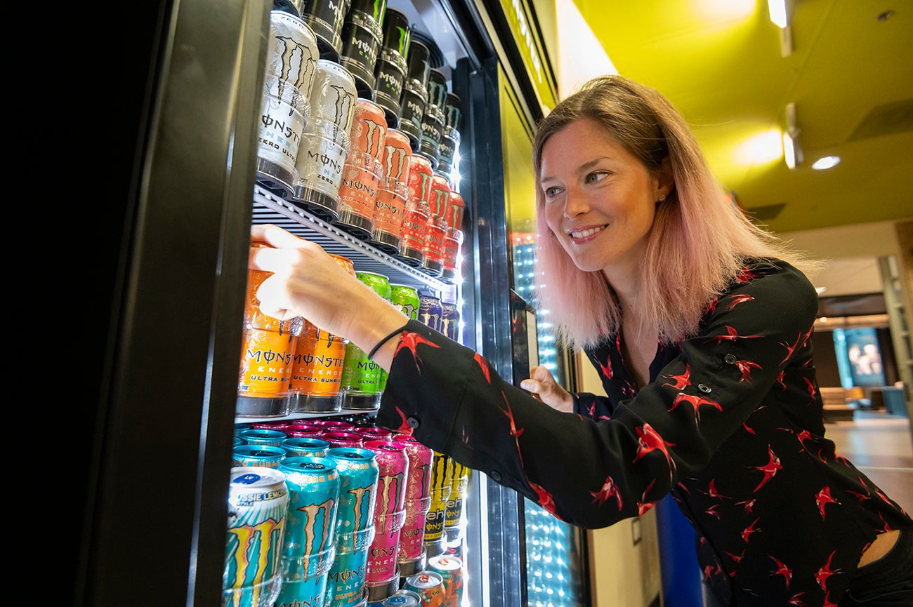 woman reaches into fridge for energy drink
