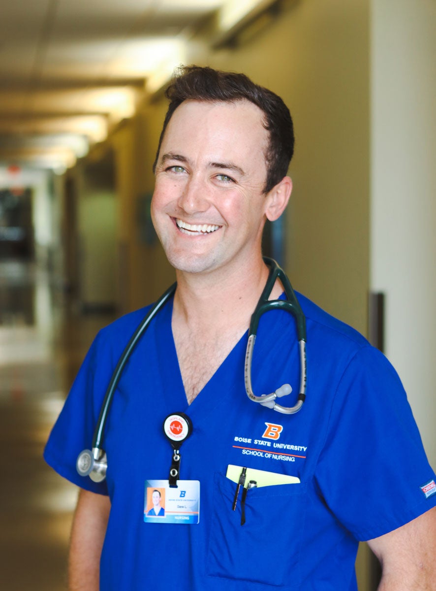 Dane Larson wears his Boise State blue scrubs and smiles with his stethoscope around his neck.