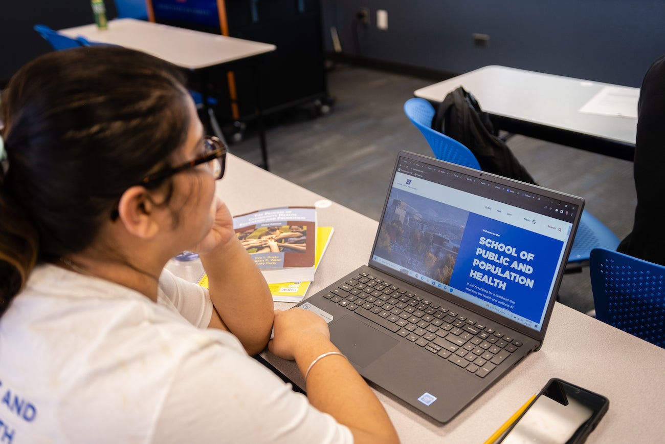 Student looks at school of public and population health website on a laptop
