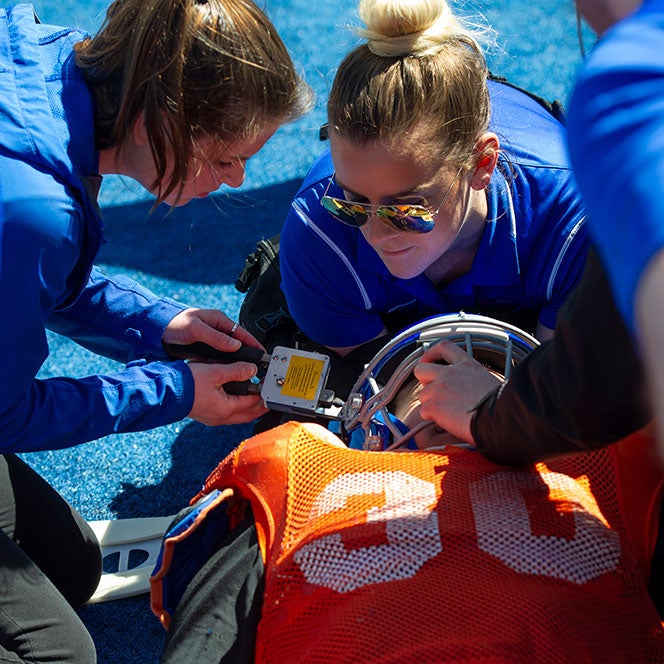 Athletic training students practice safely removing a helmet during a simulated football concussion scenario
