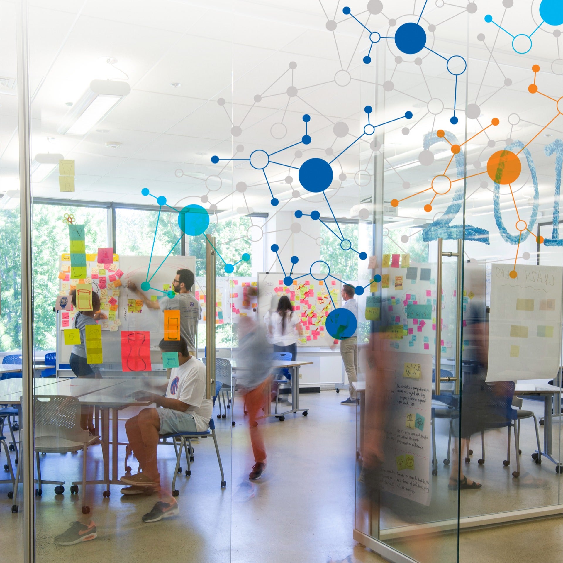 A glass wall pointed with orange and blue design and persons beyond the wall in a classroom