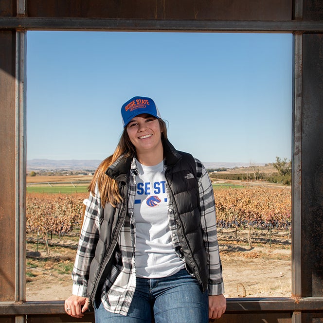 Rachel sitting in barn window, vineyards in distance behind her