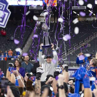 Boise State football coach hoisting Mountain West Conference Championship trophy