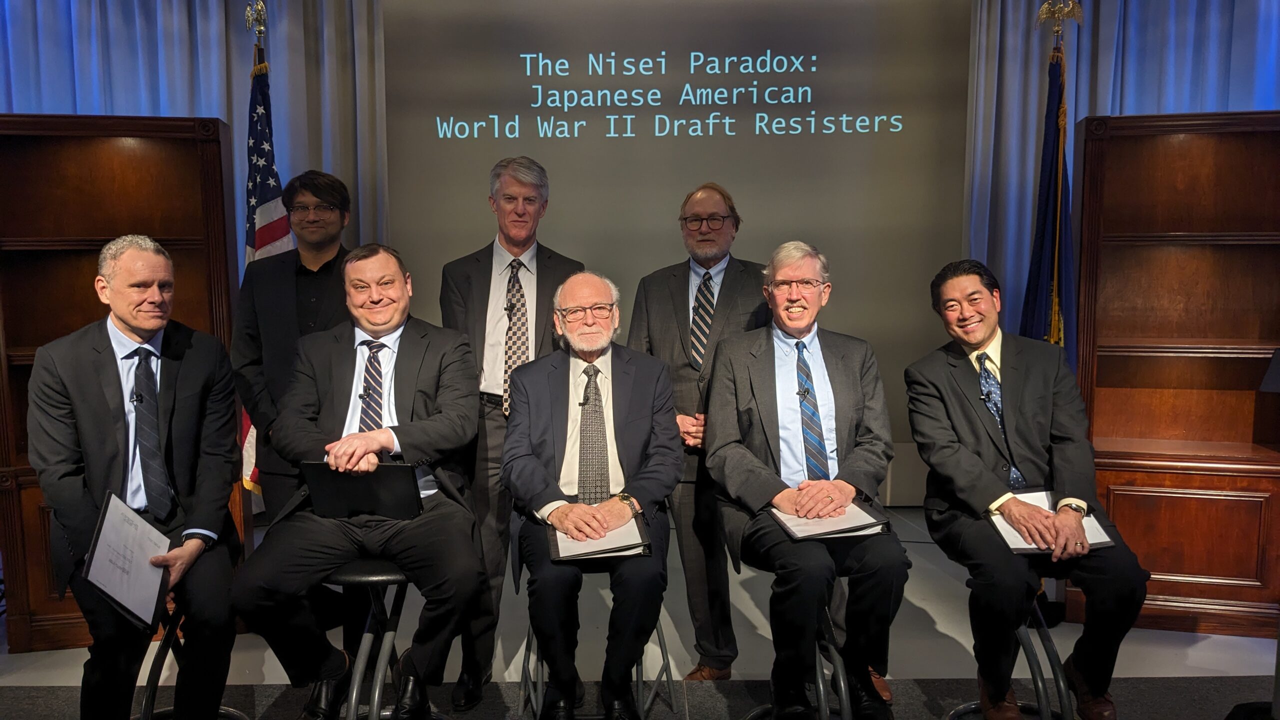 Group photo of eight men in suits.
