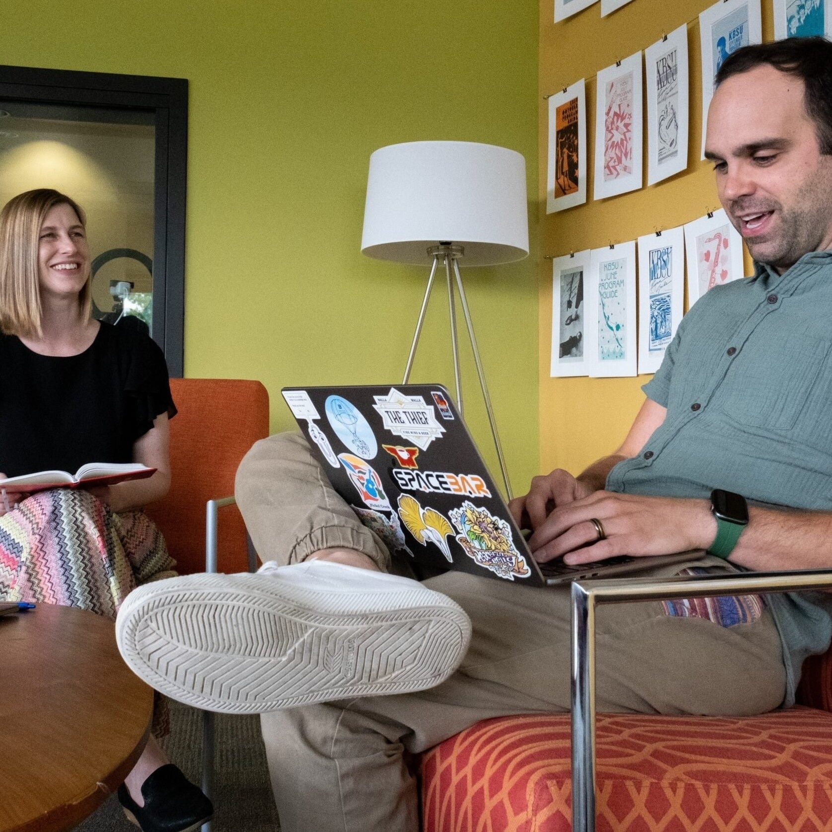 Two persons work in an office and smile