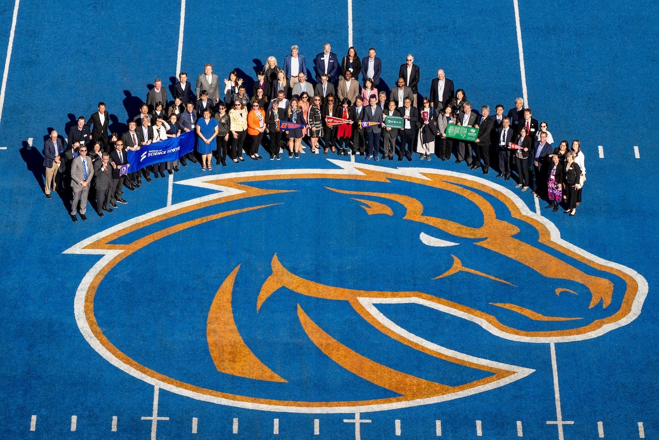 A large group poses on the blue field of Boise State