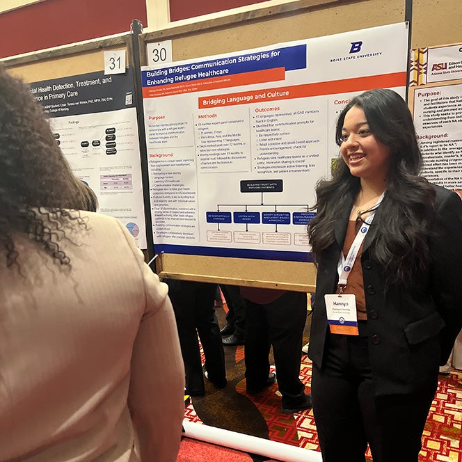 A nursing student talks to someone by her research poster.