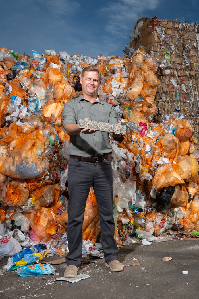 A person holds a brick of pressed plastics in a trash facility