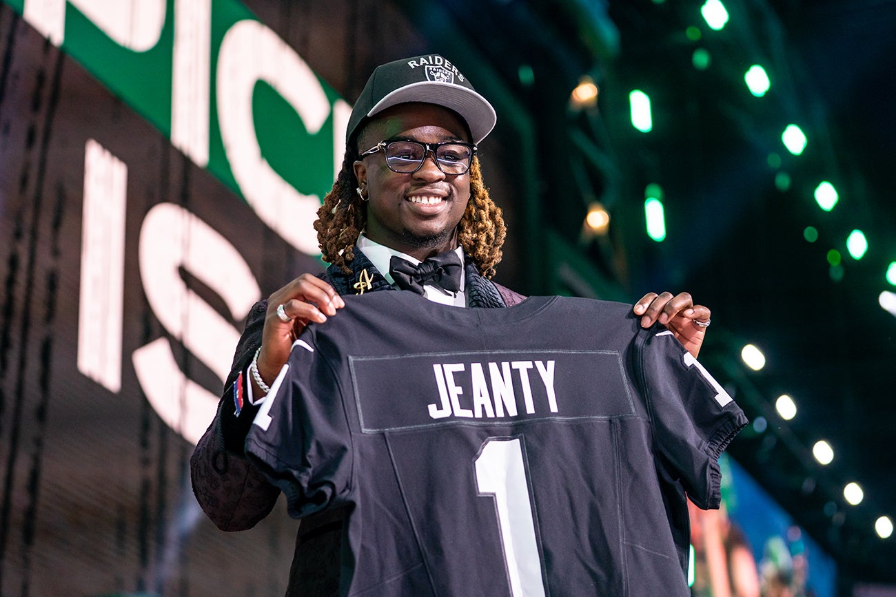 Ashton Jeanty holding a Raiders jersey at the NFL Draft.