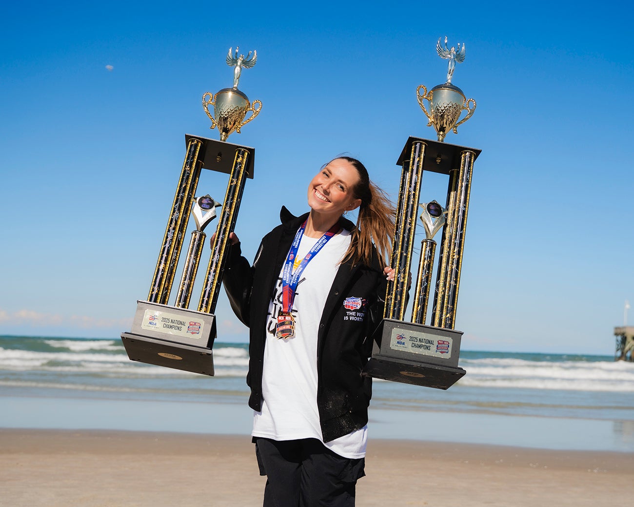 Kelsey Messer posing with two trophies on the beach