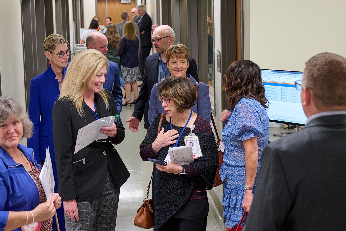 The simulation center's mock hospital hallway is filled with business people smiling and talking.
