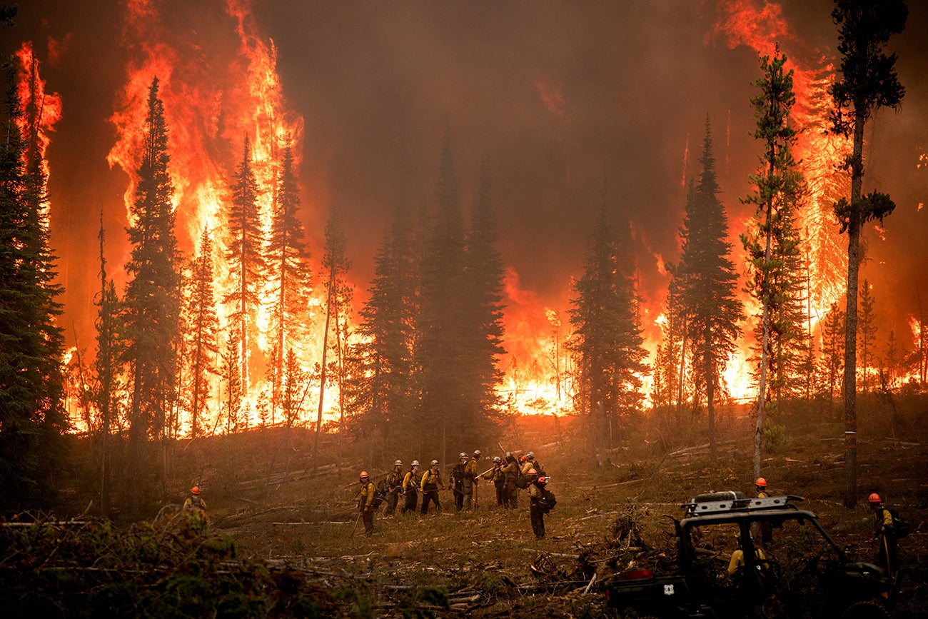 Firefighters fighting Wapiti fire with flames behind them. 