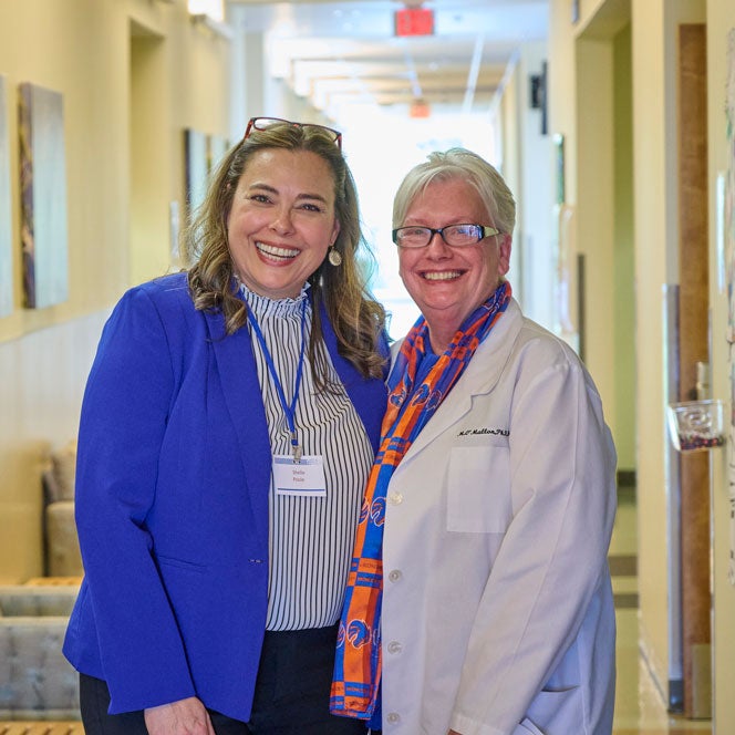 Shelle Poole and Marilyn OMallon stand and smile in the hallway.