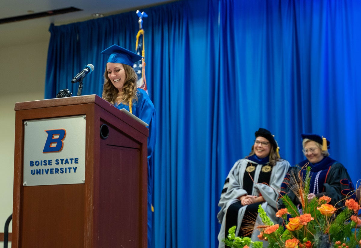 Amanda Timoney stands behind the podium as the deans of the School of Nursing sit behind her on stage.