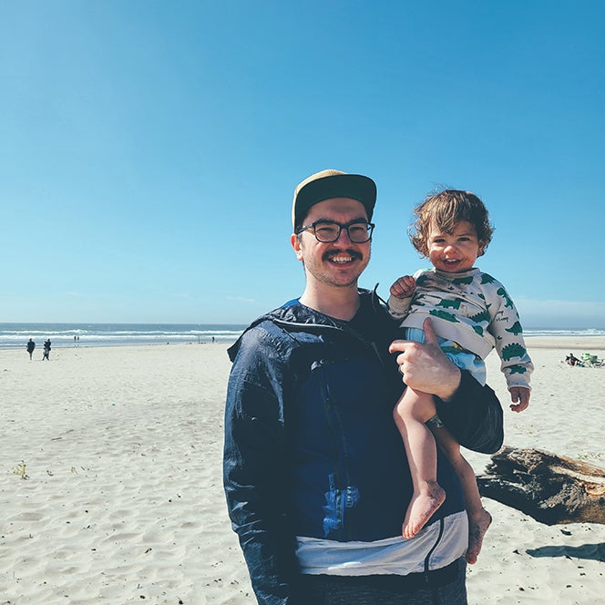 Isaiah Moroshan poses on the beach with his young child.