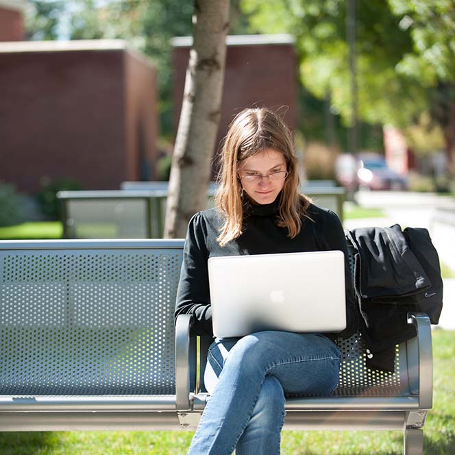 Student sitting outside, working on a laptop