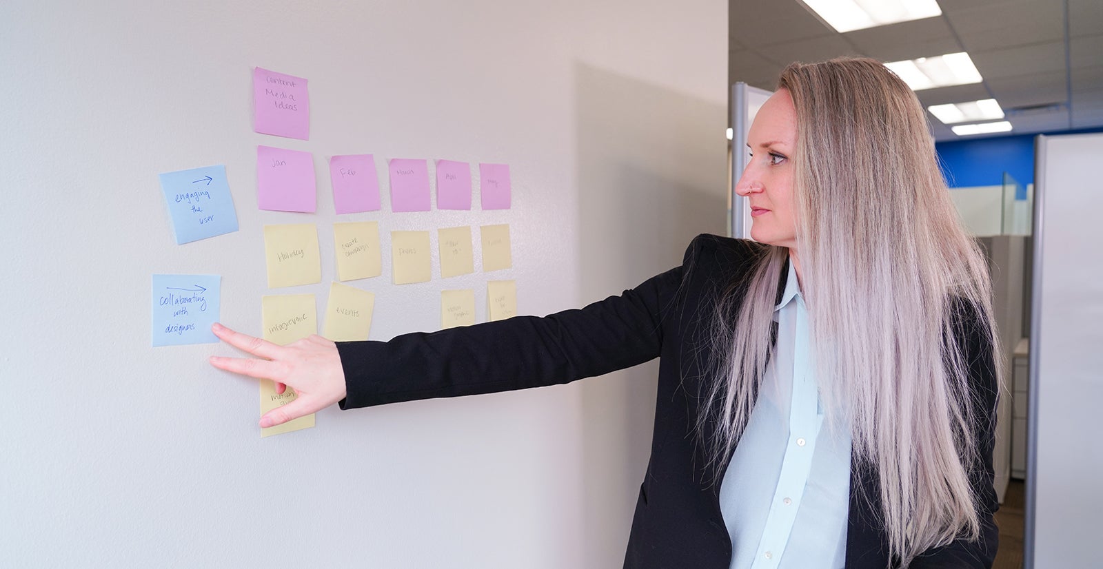 Interdisciplinary Professional Studies student, Jessi Boyer, pointing at post-it notes on a whiteboard