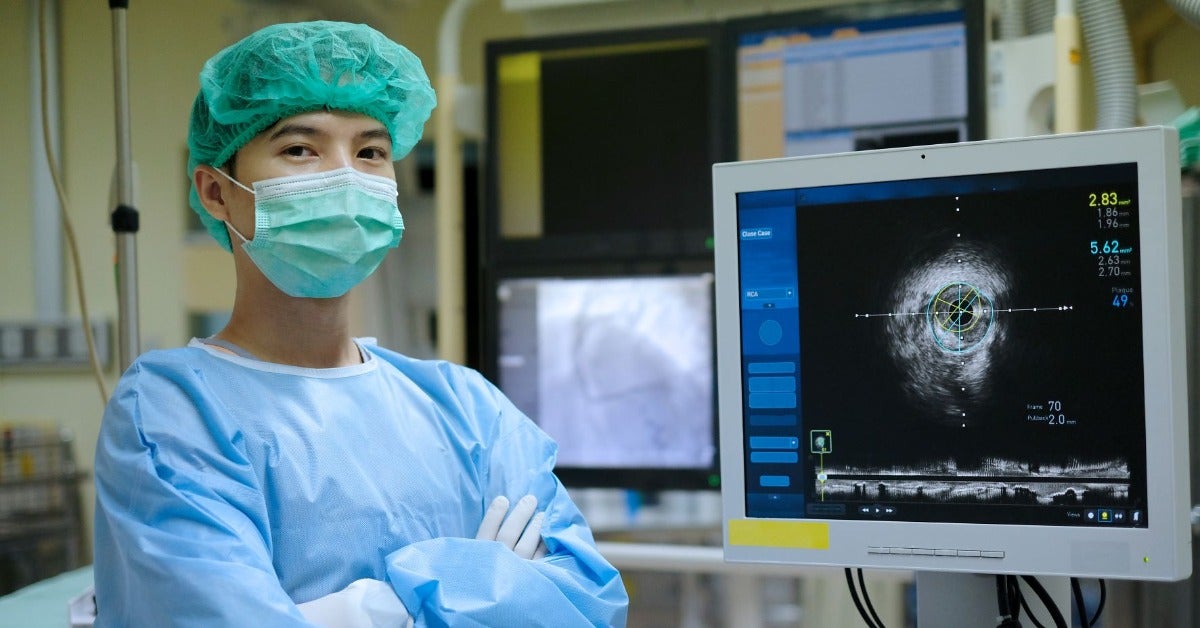 An imaging technologist stands in front of their equipment.