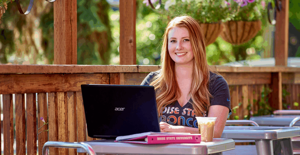 Boise State Online student with laptop sitting at coffee shop patio.