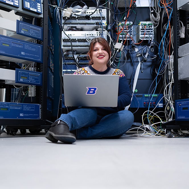 Ashley Furr sitting with her laptop in the Boise State server room